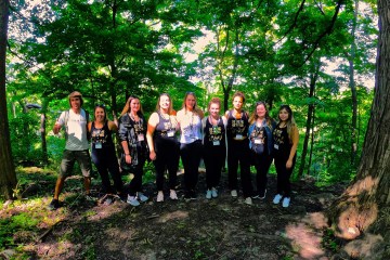 a group of people standing in front of a tree posing for the camera